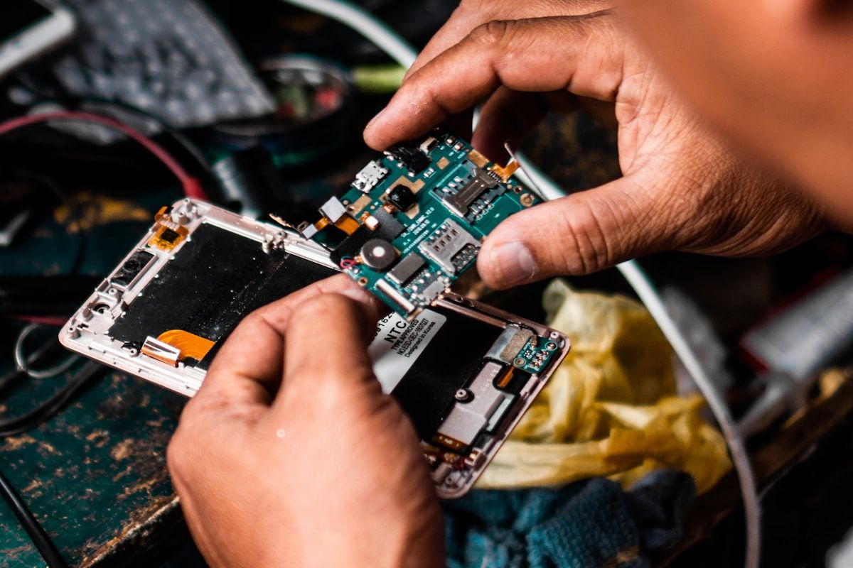 Technician performing board-level diagnostics on a mobile phone